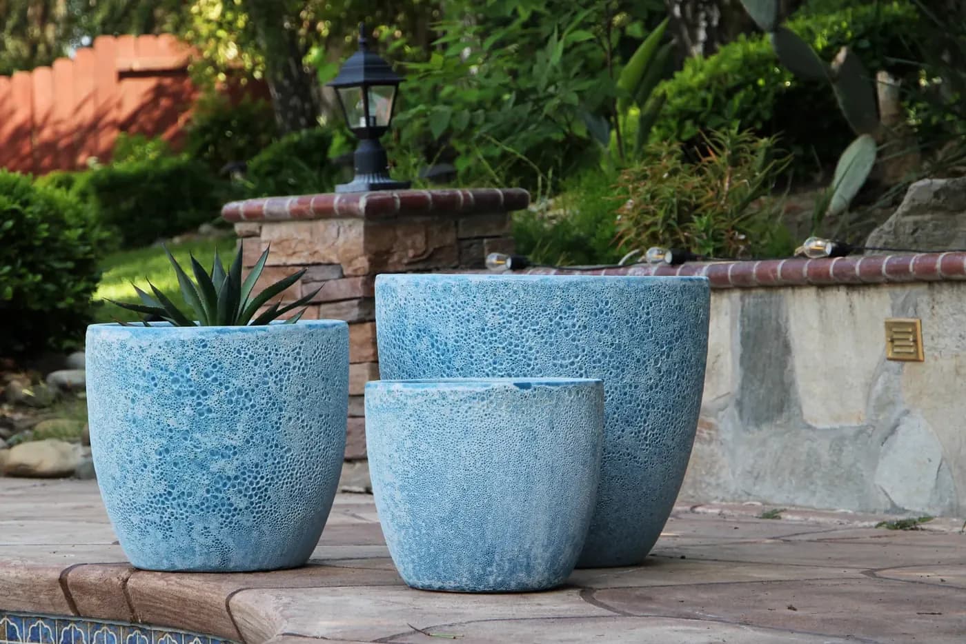 Two blue glazed pots on a timber bench in the nursery yard