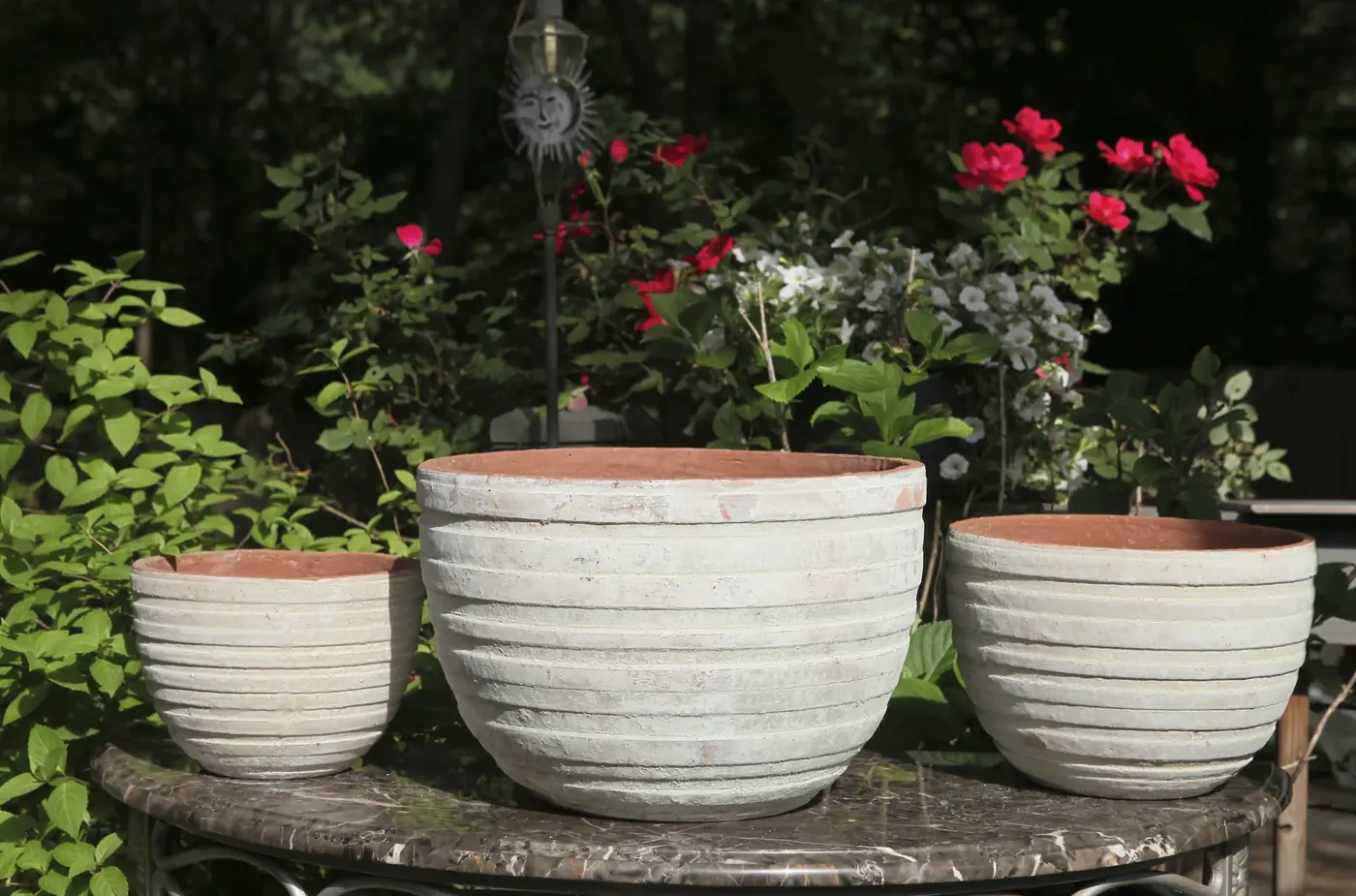 Cream and terracotta rimmed pots displayed on a garden table